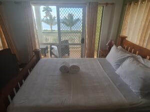 Bed with pillows and towels next to a sliding door.